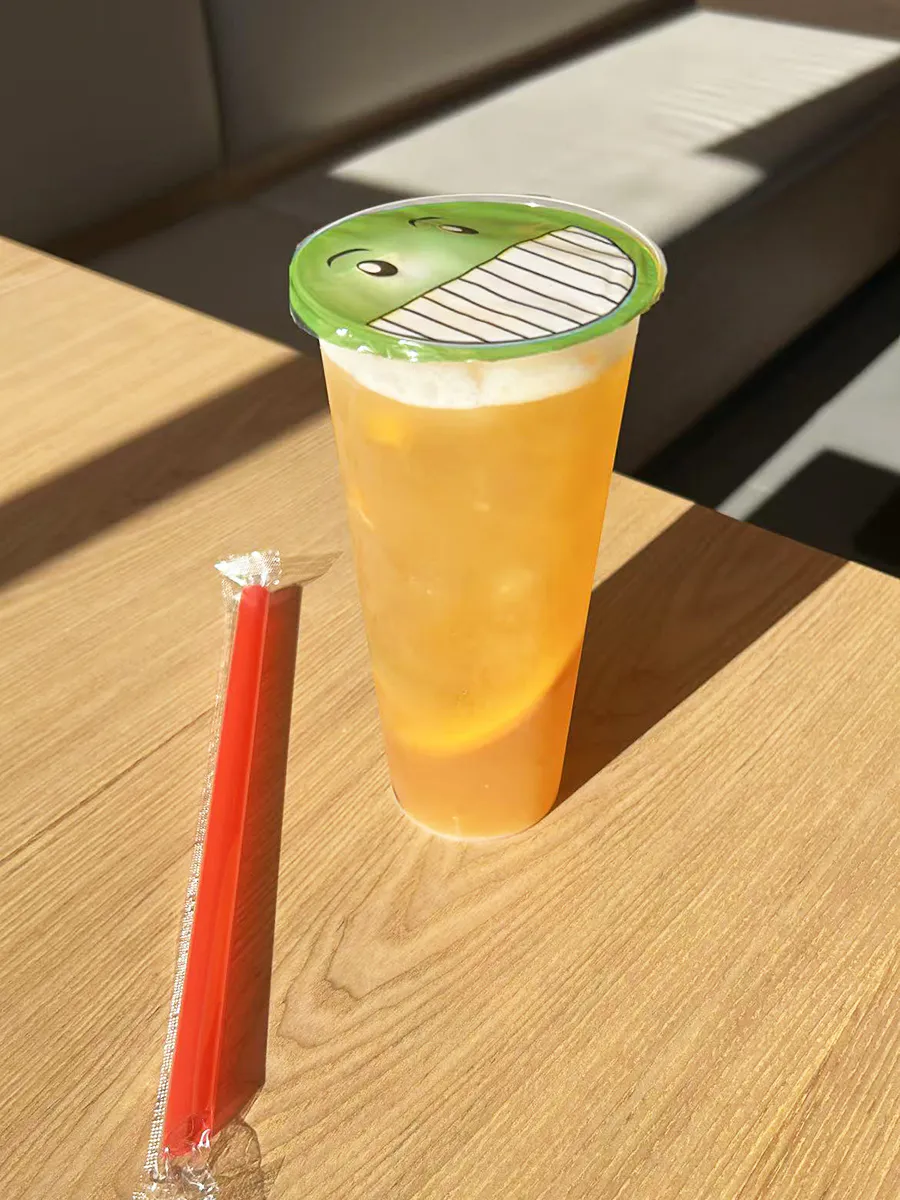 Sunlit golden peach iced fruit tea on wooden table at Mochi & Crunch Treats, a Modern Dessert Café in Tupelo