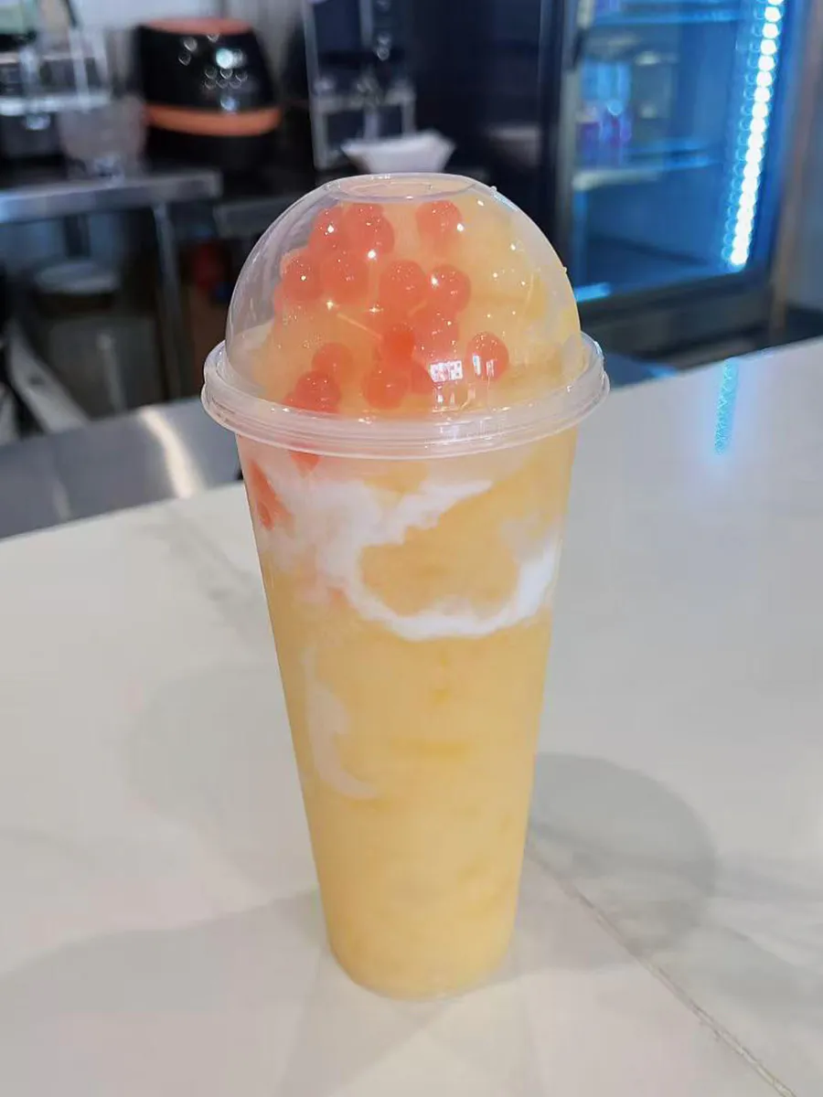 Mango fruit milk tea popping boba jelly dome top tall plastic cup at Mochi & Crunch Treats, a Modern Dessert Café in Tupelo