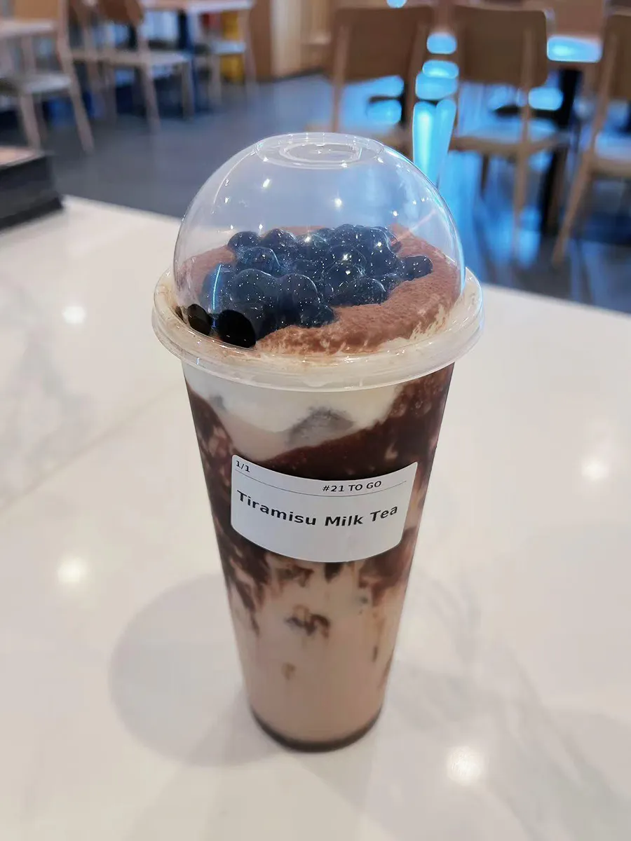Tiramisu milk tea bubble cocoa powder top dome plastic cup counter shot at Mochi & Crunch Treats, a Modern Dessert Café in Tupelo